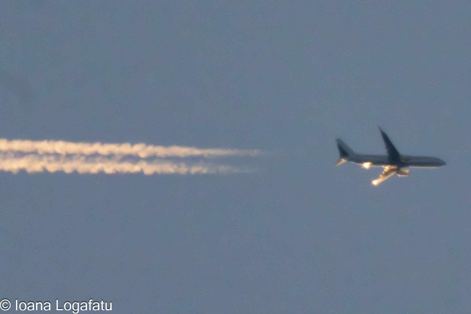 Jet soaring high with contrails
